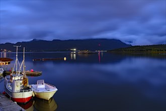 Small fishing boats reflected in the smooth water of a fjord