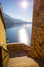 Staircase and Lake Lugano with Blue Sky and Mountain in a Sunny Day in Morcote