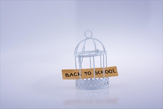 Little note about school placed in a white color bird house with metal bars