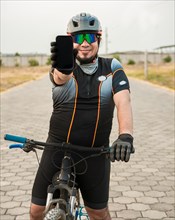 Smiling cyclist showing an advertisement on cell phone