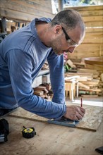 Portrait of a peeled carpenter wearing safety goggles working in the wood workshop. Copy space