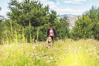 Friendly and happy dog walking in the mountains with his owner. Woman hiking with her dog. Travel with pet