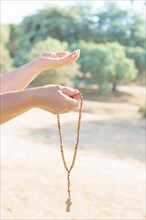 Woman's hands holding a Christian rosary with a cross