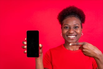 Young african american woman isolated on a red background with mobile pointing gesture