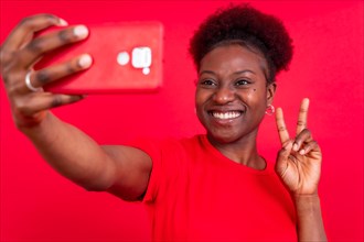 Young african american woman isolated on a red background smiling and making a selfie