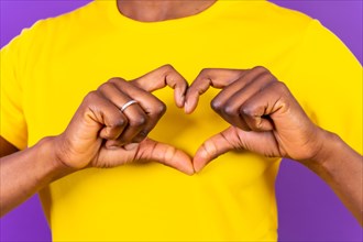 Young african american woman isolated on a purple background smiling and heart gesture