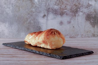 Puff pastry horn filled with pastry cream on a black blackboard on a wooden table