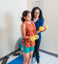 Physiotherapist helping patient with dumbbells
