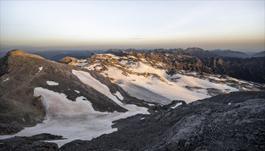 View of rocky plateau with snow and glacier at sunrise