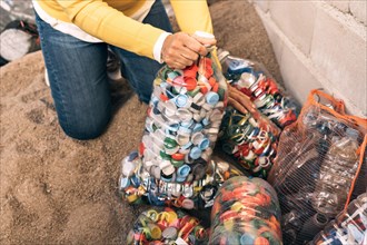 Close-up detail of a woman's hands sorting large amount of colorful plastic bottle caps. Recycling center