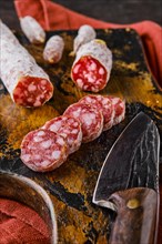 Fermented salami sausages on wooden cutting board cut on slices