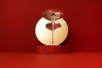 Round mirror with a stage on a bright red background. Retro glass of sparkling champagne is reflected in the mirror. Holliday concept