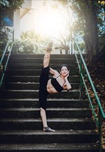 Dance artist girl doing acrobatics and flexibilities in heels. Dance girl doing flexibility on the stairs outdoor. Portrait of woman dancer in heels doing yoga flexibilities