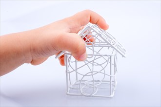 Little model house made of metal bars in hand on a white background