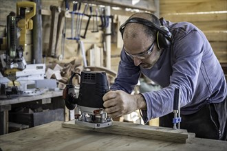 Close-up of carpenter sanding a wood with orbital sander in a workshop