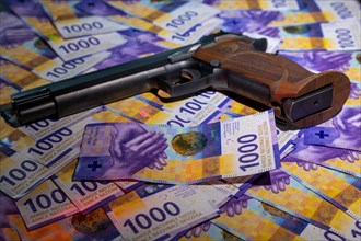 Elegant Semiautomatic 9mm Handgun with Swiss Helvetia Symbol Leaning on Swiss Franc 1000 Banknote in Switzerland