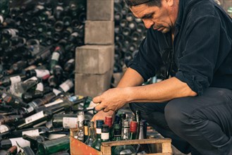Male volunteer working at a recycling centre. Glass bottles prepared for recycling. Concept of responsibility