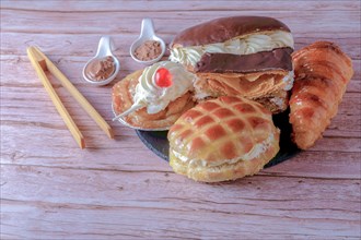 Top view of an assortment of cream and custard cakes on a black slate and gray background