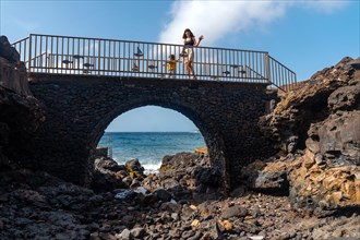 A mother with her son on a stone bridge by the sea in El Hierro