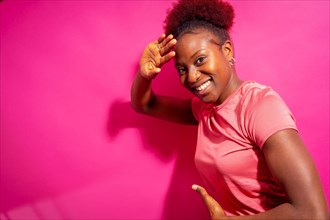 Young african american woman isolated on a pink background smiling and dancing