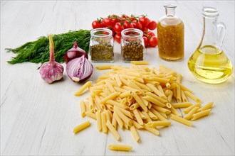 Uncooked pasta farfalline scattered on the table surrounded with ingredients