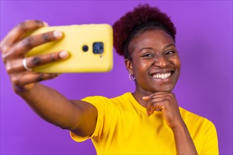 Young african american woman isolated on a purple background smiling and making a selfie