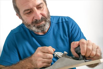Front view of a bearded male carpenter planing wood with a hand planer isolated on white background