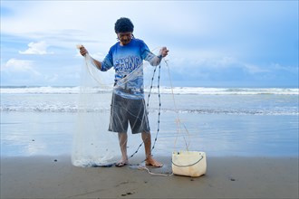 Front view of a fisherman on the shore preparing his net. Concept Lifestyle of a fisherman in the pacific sea