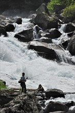 Angler fly fishing at waterfall of the gave de Jeret in the Hautes-Pyrenees near Cauterets