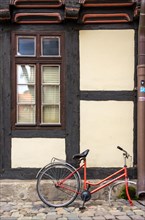 Broken and abandoned bicycle in front of historic half-timbered architecture with ship's throats in hell