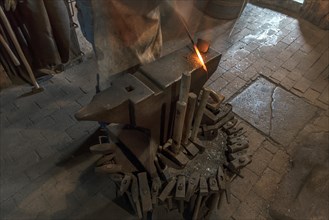 Glowing iron on the anvil with forging hammers in a historic hammer mill from the 19th century