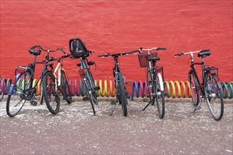Bicycles standing in front of a red wall