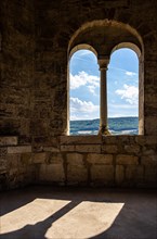 View through a window of the west tower of the Romanesque monastery ruins of St. Wigbert at surrounding structures in the village of Goellingen near Bad Frankenhausen in Kyffhaeuserland