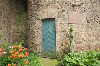 Sculpture and door with inscription and flowers at the Thieves' Tower