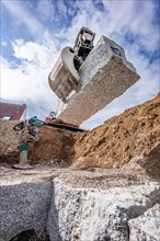 Excavator grab with stone on construction site