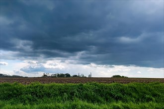 Dark rain clouds hovering over arable land field for agriculture agricultural use