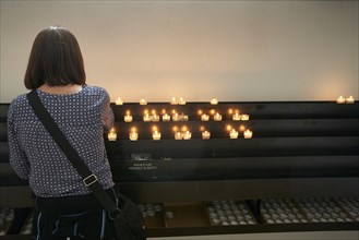 Woman in front of offering candles in church