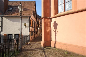 Narrow alley with alleyway lamp between church and half-timbered house
