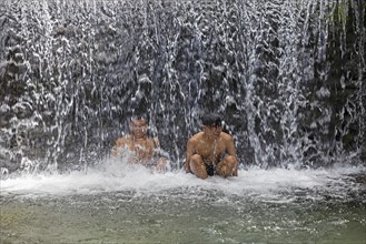 Two Indonesian boys bathing in the Benang Kelambu Waterfalls on the slopes of the Rinjani volcano