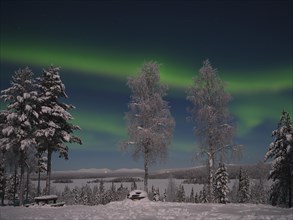 Northern Lights above Lake Saerkijaervi with a view of the mountains of Pallas Yllaestunturi National Park