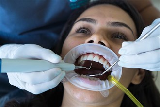 A woman's teeth are being treated at the clinic. An orthodontist uses dental instruments to place braces on a patient's teeth. Selective focus. Concept of whitening