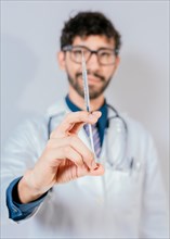 Close up of doctor holding a syringe isolated. Smiling doctor holding a syringe on isolated background