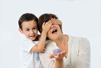 A child surprises his mom with a special gift on her birthday. Studio portrait on white background