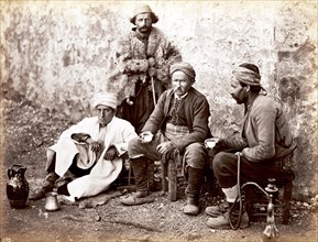 Four men with coffee cup and hookah in front of a cafe in Constantinople