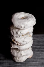 Sugar doughnuts glazed with icing sugar stacked in a pile on a black background and copy space