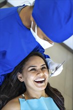 Female patient smiles and looks at her dentist while she is being treated in the dental office. Concept of whitening