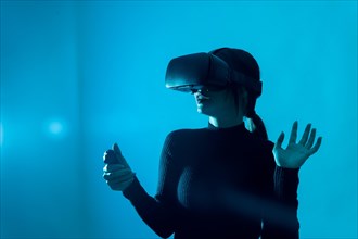 Metaverse technology concept. Woman in virtual reality VR glasses on a blue background. Futuristic lifestyle