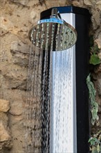 Shower in the street over a stone wall spraying water