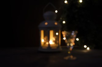 Shiny blurred background for design. Glass with white wine with garland lights and candle lantern blurred. Night picture. Beautiful lights