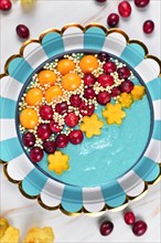 Blue fruit smoothie bowl dyed with natural spirulina powder decorated with cranberries